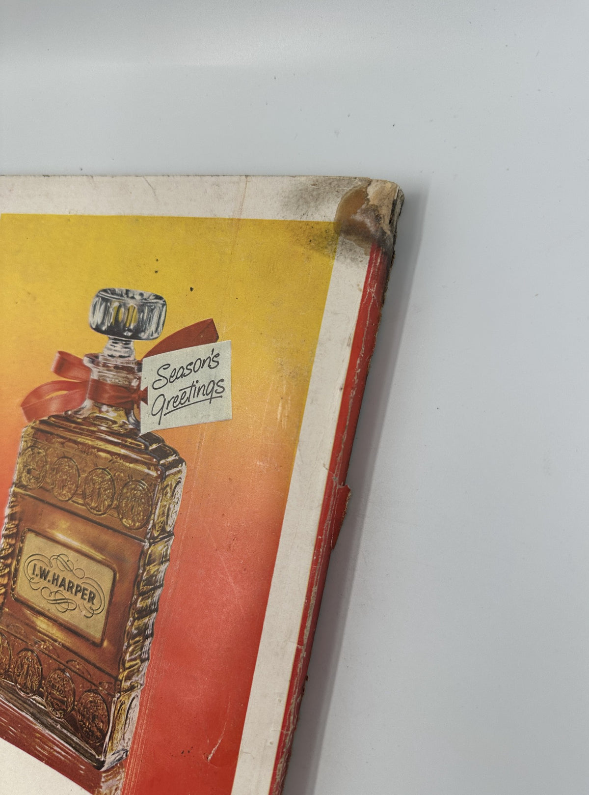 Close-up view of the cover corner of Esquire Magazine December 1950 featuring promotional art for I.W. Harper whiskey with a festive greeting. The magazine is in acceptable condition, showing significant wear.