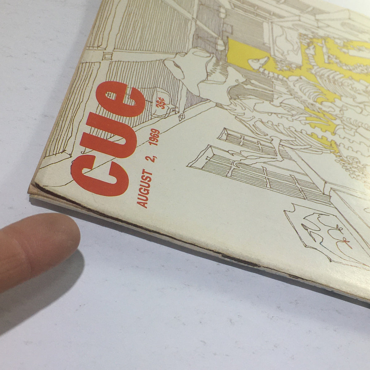Close-up view of the spine and cover details of Cue Magazine from August 2, 1969, highlighting the title and design featuring dinosaur fossils.