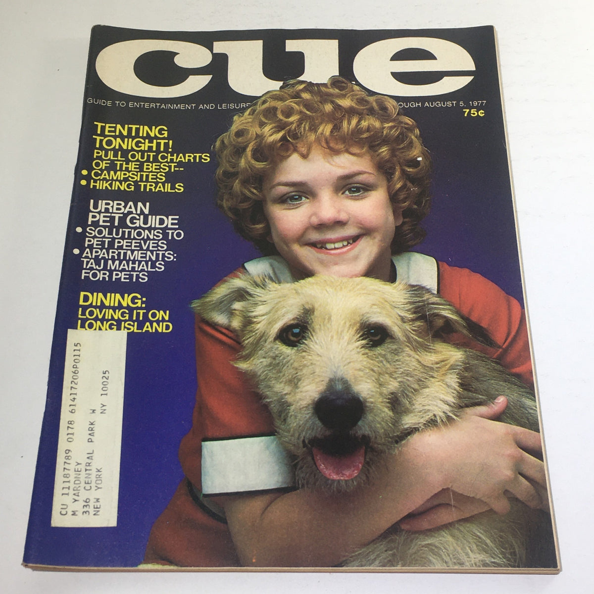 Cover of Cue Magazine: August 5 1977 featuring a young girl with curly hair smiling while holding a dog. The cover highlights articles about camping, pet care, and dining in Long Island.