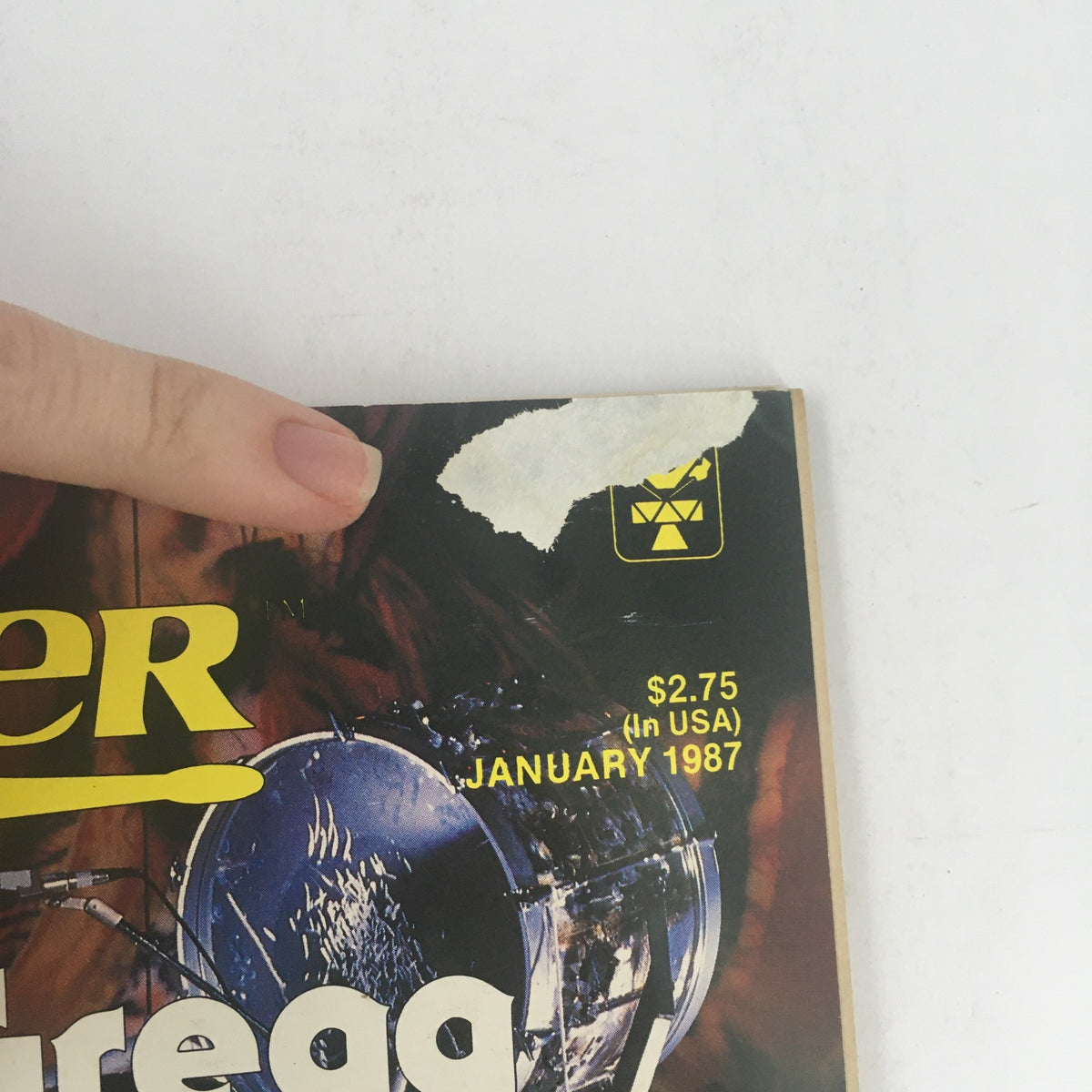 Cover of Modern Drummer Magazine January 1987 featuring drumming elements, price tag, and a finger pointing at the top corner. Key features include talents of Gregg Bissonette, Gary Husband, and Woody Herman.