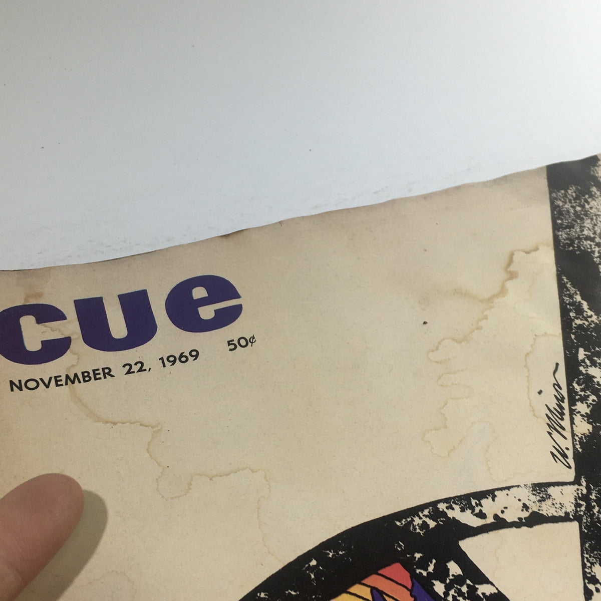 Close-up of the top corner of Cue Magazine: November 22, 1969, featuring the magazine's title and date, along with noticeable vintage stains adding to its historical charm.