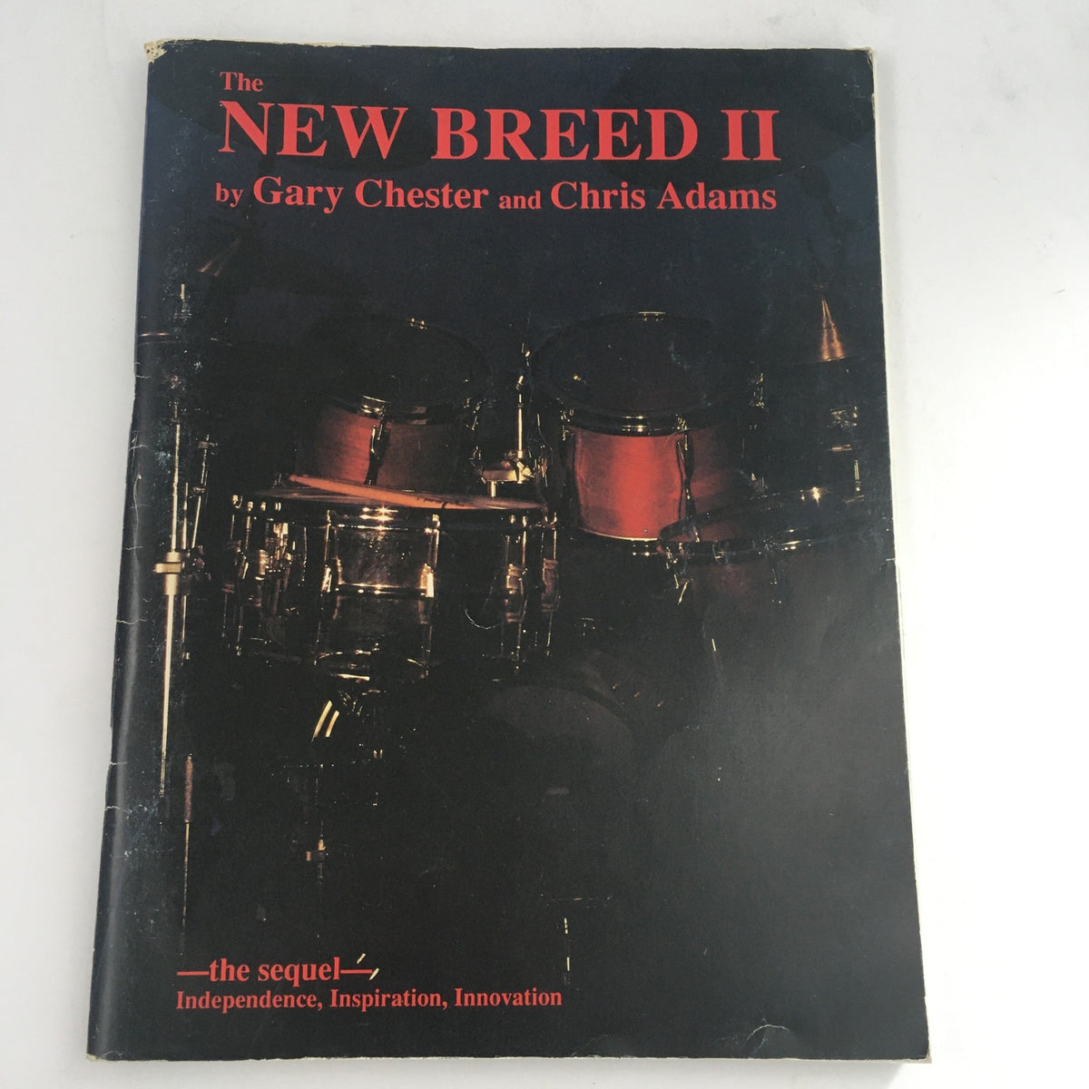 Cover of 'The New Breed II' by Gary Chester and Chris Adams, featuring a drum set, highlighting the book's focus on independence, inspiration, and innovation in drumming.
