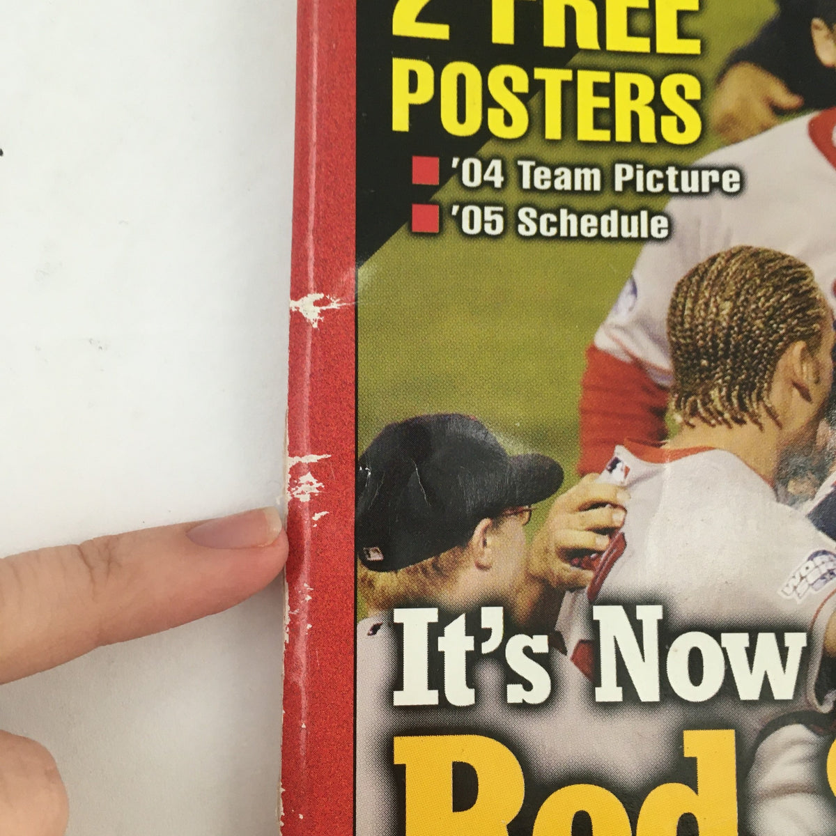 Close-up of the spine of the 2005 Red Sox Championship Almanac, showing details on the cover including '2 Free Posters', '04 Team Picture', and '05 Schedule', highlighting its collectible condition.