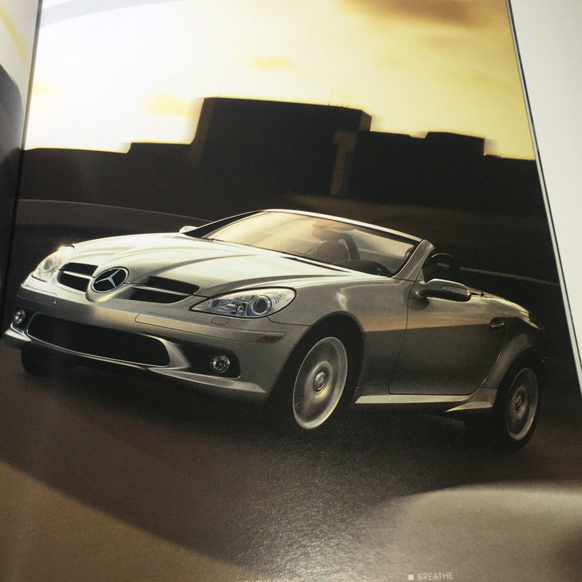 2005 Mercedes-Benz SLK-Class 350 55 AMG auto brochure image showing the car in a dynamic driving pose.