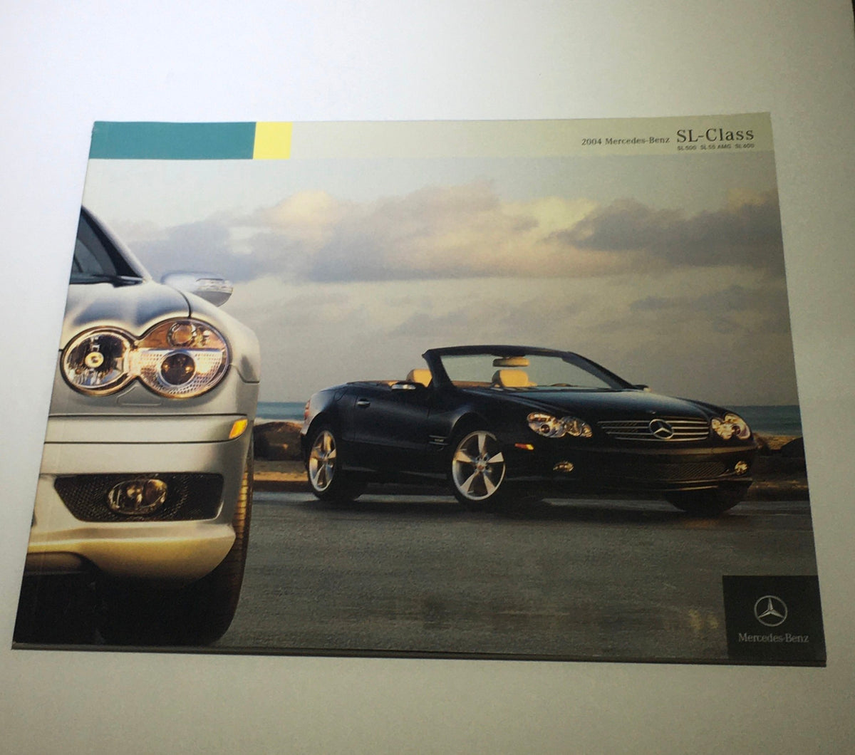 2004 Mercedes-Benz SL-Class 500 600 AMG Dealership Car Auto Brochure Catalog featuring a sleek convertible sports car against a coastal backdrop.