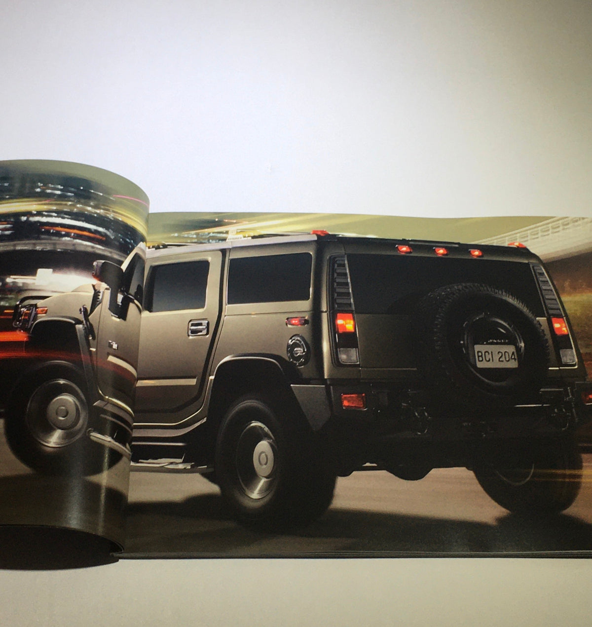 A spread from the 2006 Hummer H2 SUV SUT Dealership Car Auto Brochure Catalog showcasing the rear view of a Hummer H2 in a dynamic city setting.