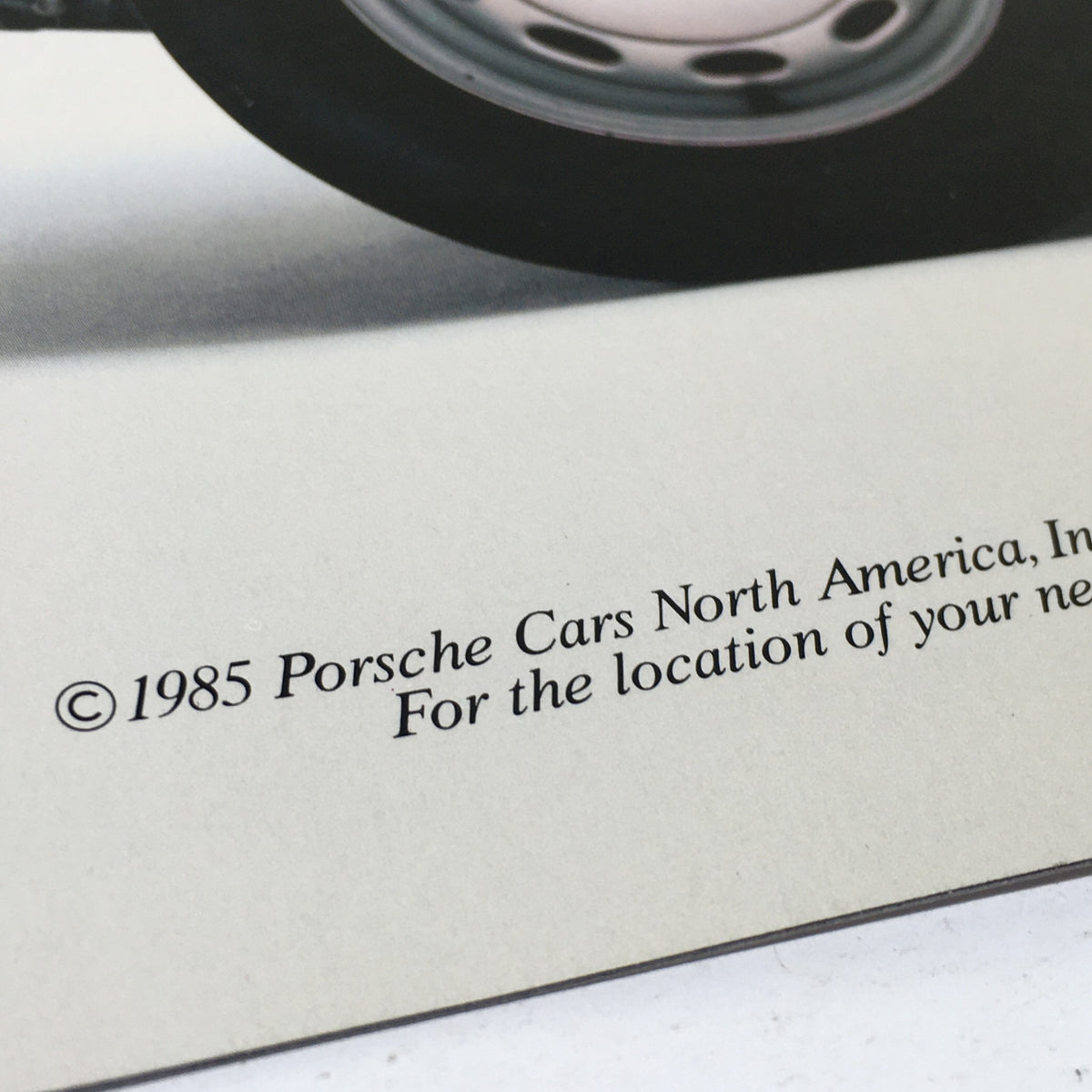 Close-up of the bottom section of the back cover of the 1985 Porsche 911 Carrera & 356-001 Dealership Car Auto Brochure Catalog featuring the copyright notice and additional contact information for Porsche.