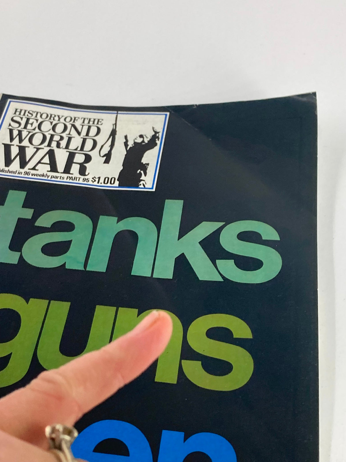 Close-up of the cover of VTG History of the Second World War Part 95, 1975 edition, showing the title 'The Tanks, Guns & Men' with a finger pointing at the lettering and the military illustration in the corner.