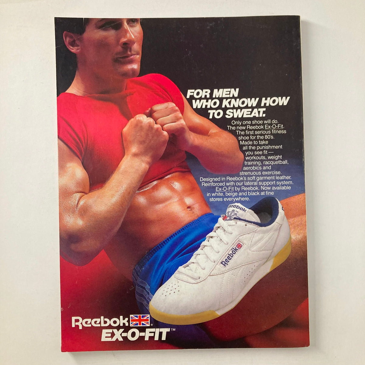 Illustration from Joe Weider's Muscle & Fitness Magazine February 1985 featuring a male model in a red workout shirt showcasing the Reebok Ex-O-Fit fitness shoe. The advertisement highlights the shoe's design for rigorous workouts, emphasizing its suitability for serious fitness enthusiasts.