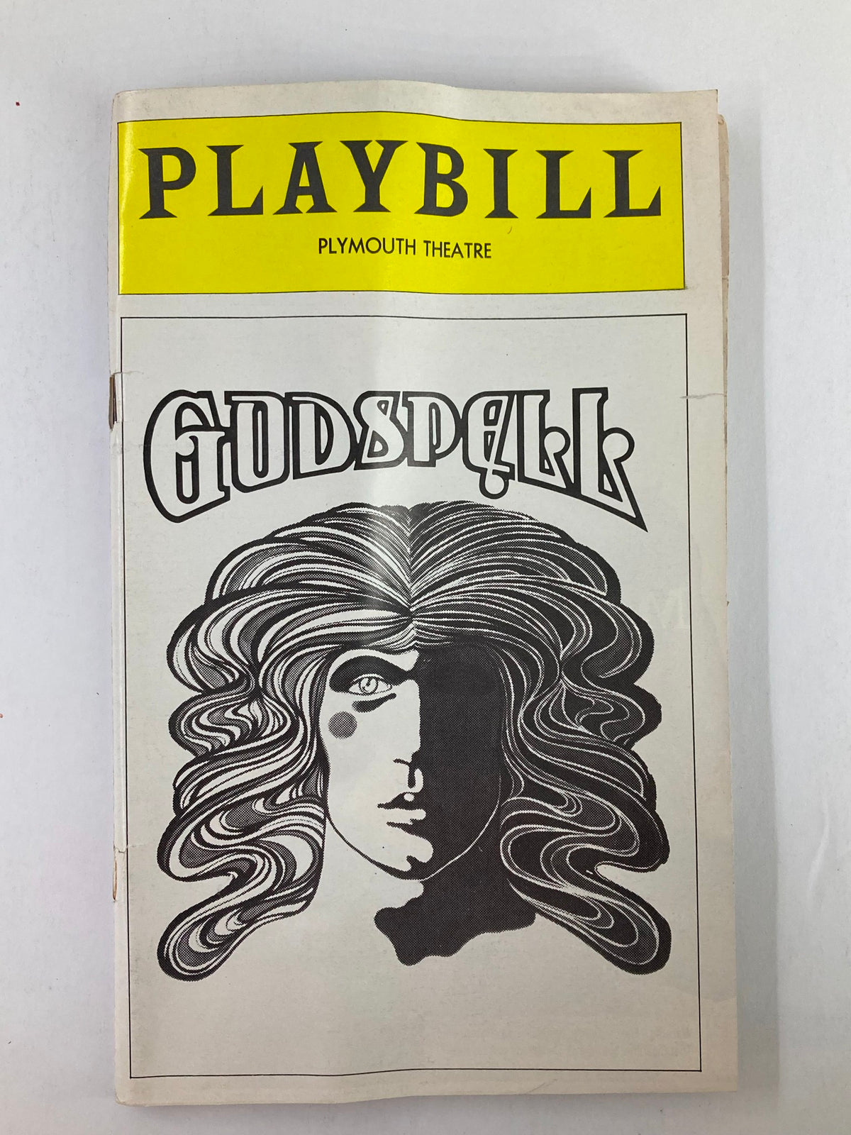 1976 Playbill from the Plymouth Theatre featuring the musical Godspell, showcasing a graphic cover design resembling long hair and a face, representing themes from the show.