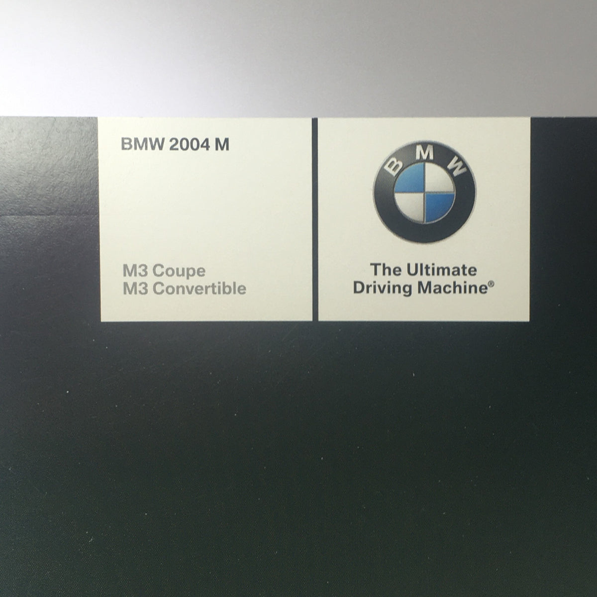 2004 BMW M3 Coupe - Convertible Dealership Car Auto Brochure detail showcasing the BMW logo and information about the M3 Coupe and M3 Convertible.