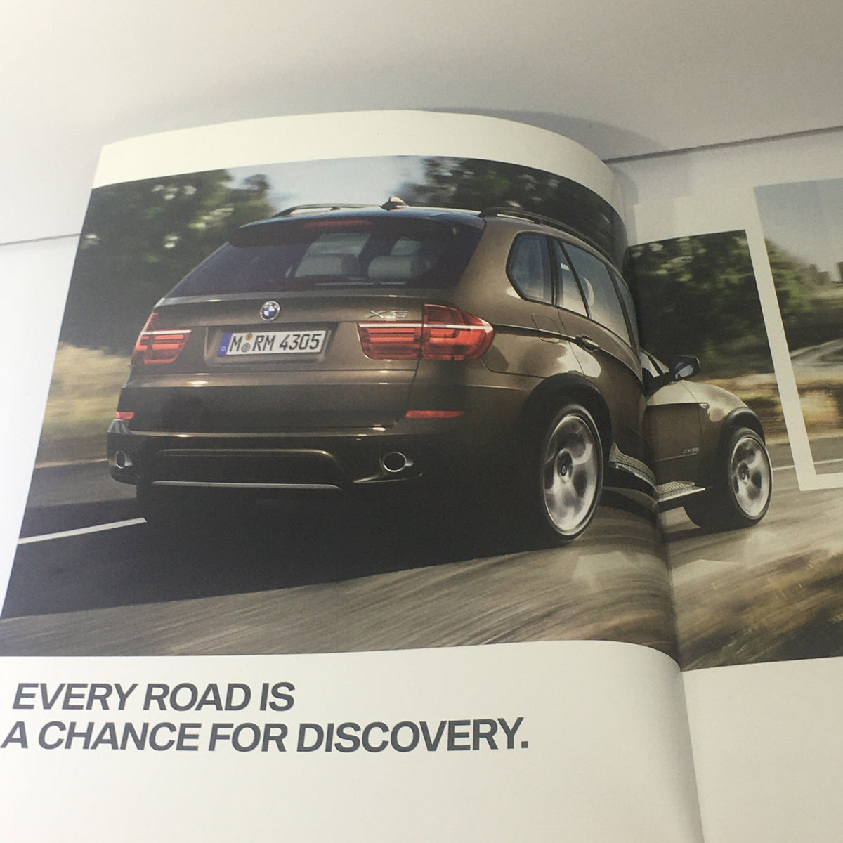 Interior page of the 2011 BMW X5 Sports Activity Vehicle Dealership Car Auto Brochure showcasing a brown BMW X5 with the caption 'Every road is a chance for discovery'.