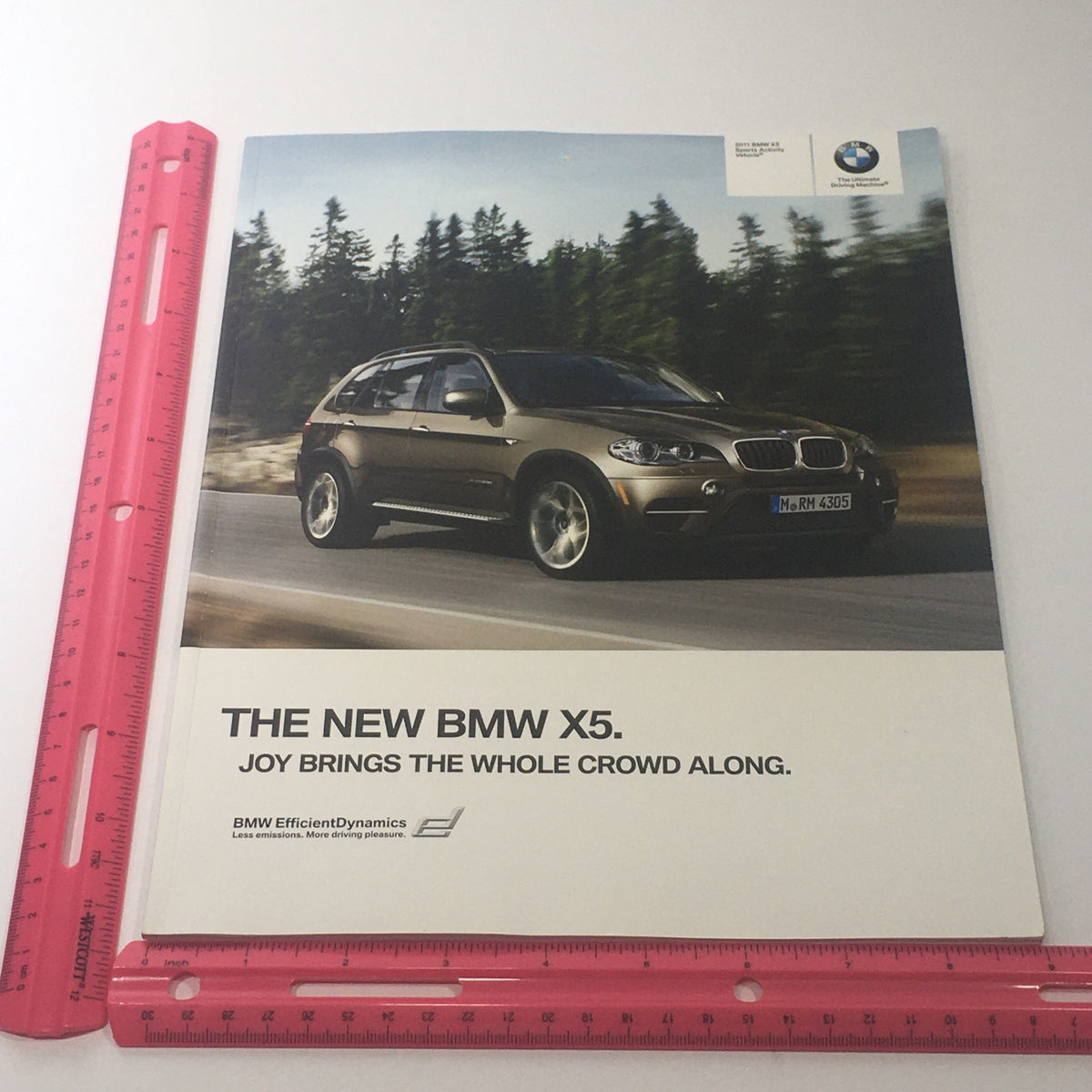 Front view of the 2011 BMW X5 Sports Activity Vehicle Dealership Car Auto Brochure featuring the headline 'The New BMW X5. Joy Brings the Whole Crowd Along'.