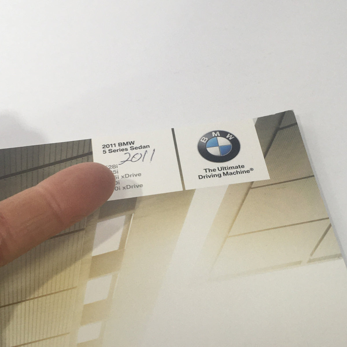 Close-up of the 2011 BMW 5 Series Sedan brochure details highlighting the models 528i, 535i, and 550i along with the BMW logo.
