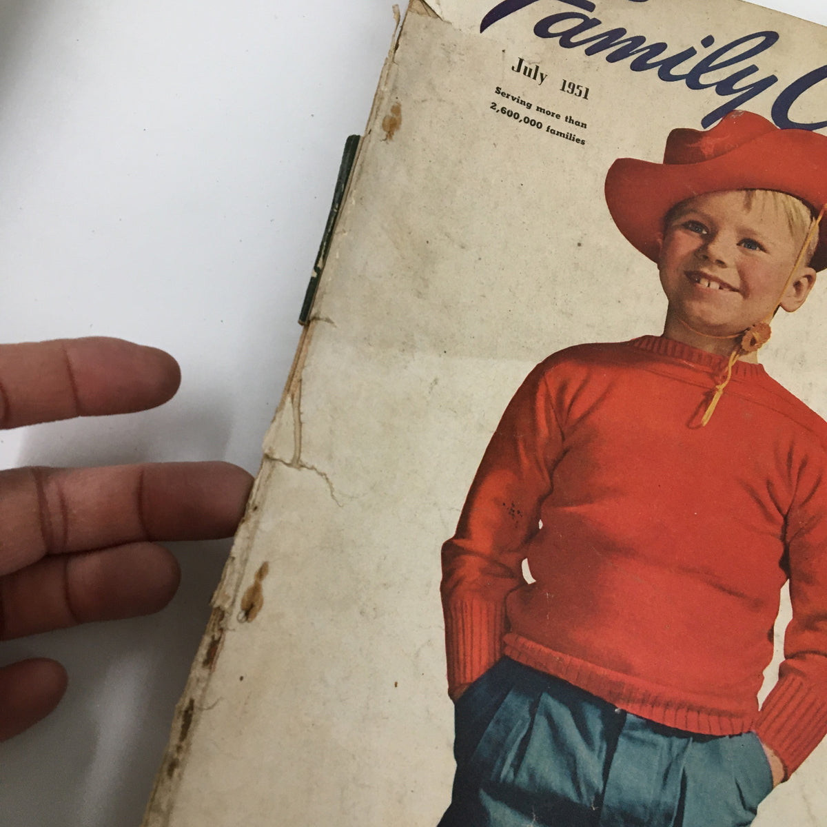 Close-up shot of the cover of VTG Family Circle Magazine July 1951 showing a child in a red sweater and hat, highlighting vintage magazine details.