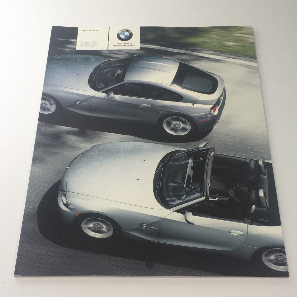 Cover of the 2007 BMW Z4 Roadster Coupe 3.0i 3.0si Dealership Car Auto Brochure Catalog featuring aerial view of two silver BMW Z4 cars on a scenic road.