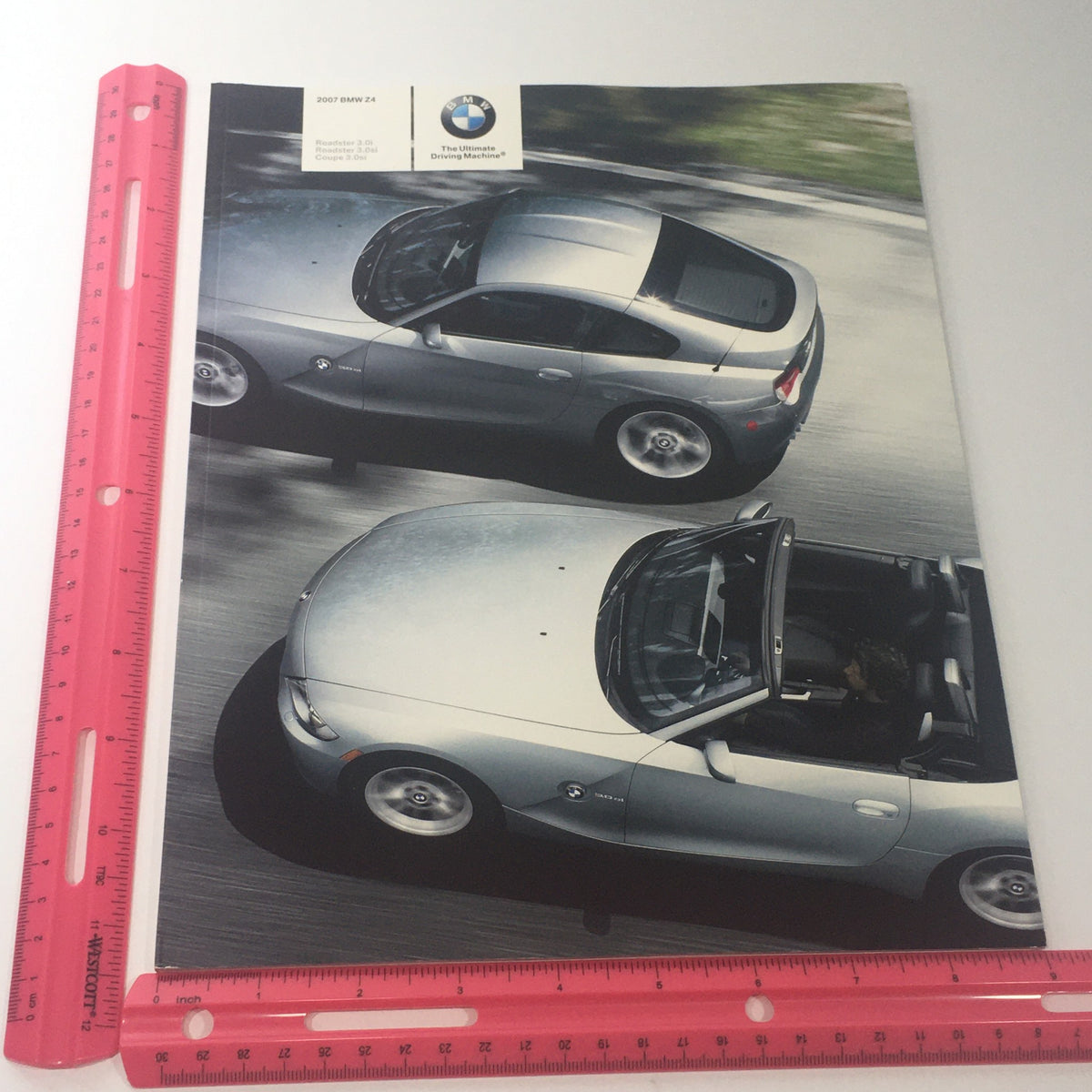 Image showing the 2007 BMW Z4 Roadster Coupe 3.0i 3.0si Dealership Car Auto Brochure Catalog with a ruler for size reference, highlighting its cover featuring two BMW Z4 cars.