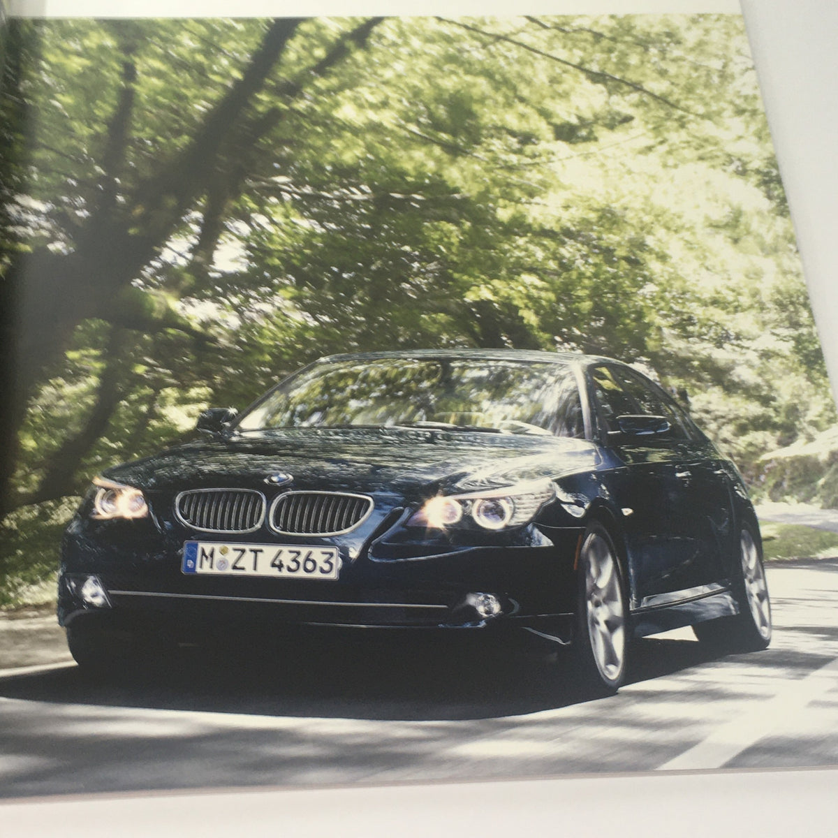 2008 BMW 5 Series Sedan 528i 528xi 535i Dealership Car Auto Brochure Catalog featuring a dynamic view of the BMW sedan driving on a tree-lined road, highlighting its elegant exterior.