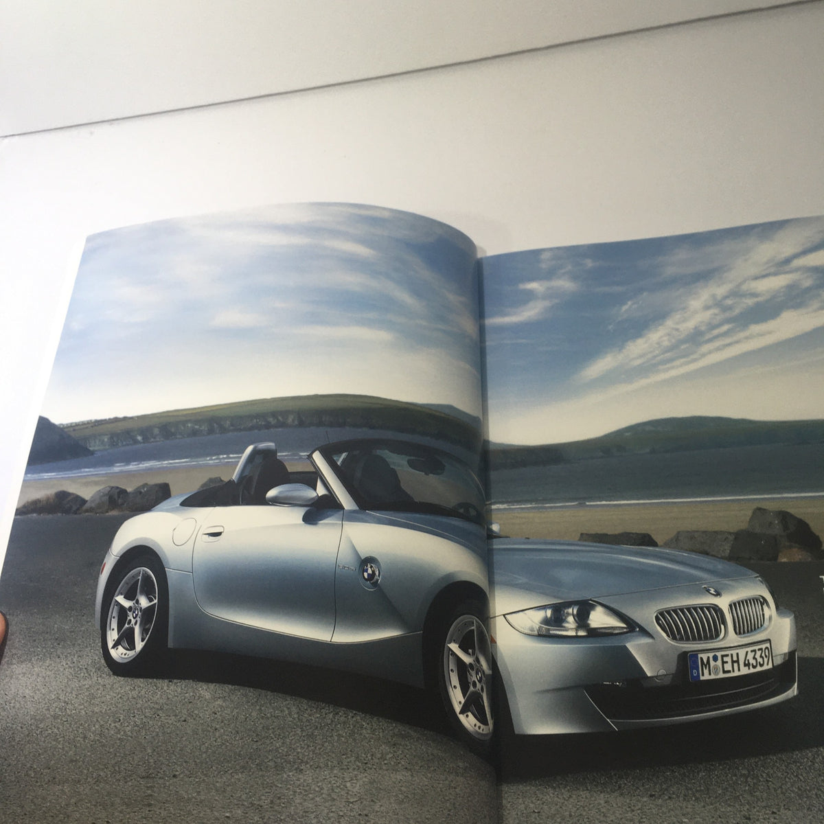 2007 BMW Z4 Roadster 3.0i 3.0si Coupe - Elegant silver convertible showcased against a scenic coastline in the dealership catalog.