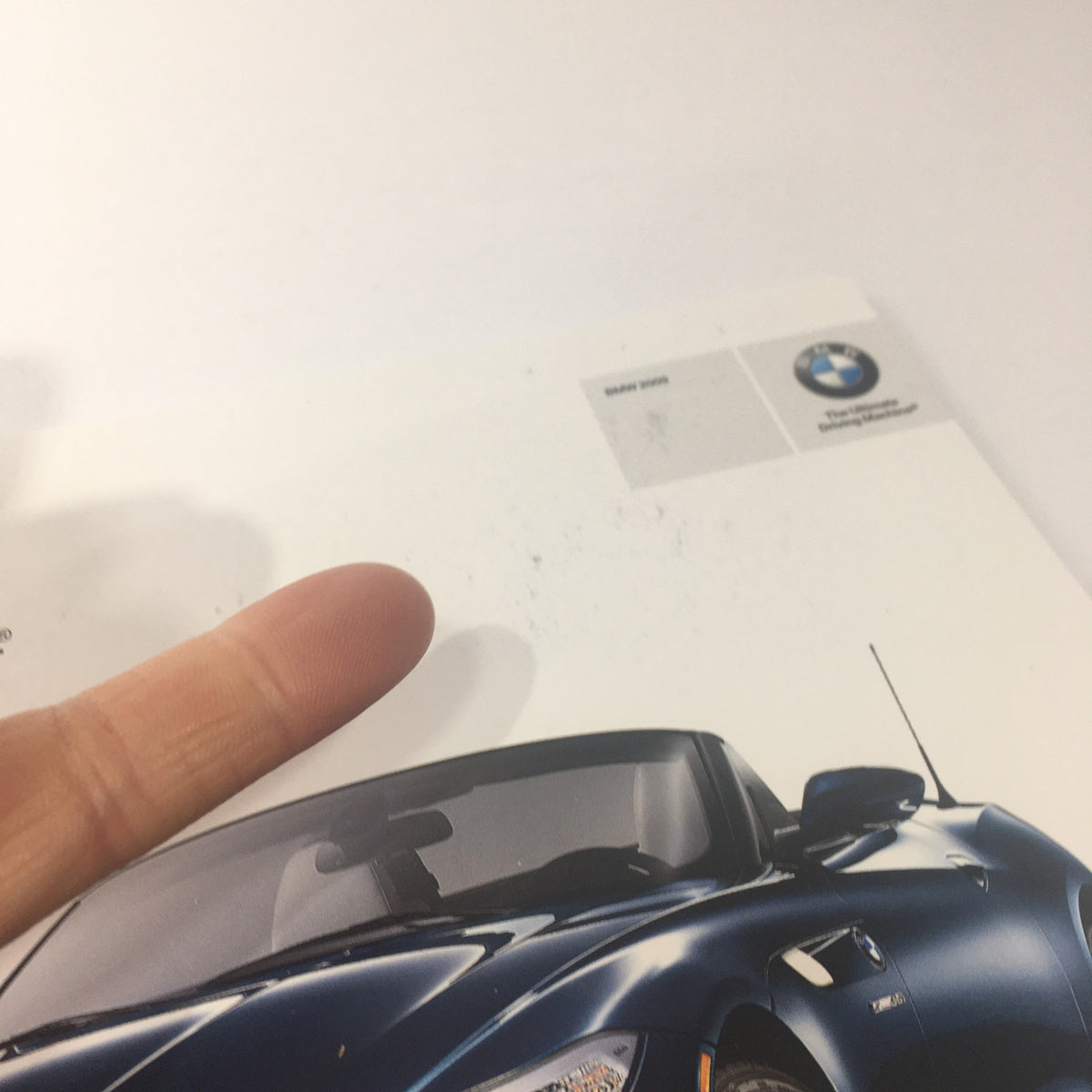 Close-up of the 2009 BMW Full Line Dealership Car Auto Brochure Catalog cover showing wear with finger pointing at marks. Perfect for vintage brochure collectors.