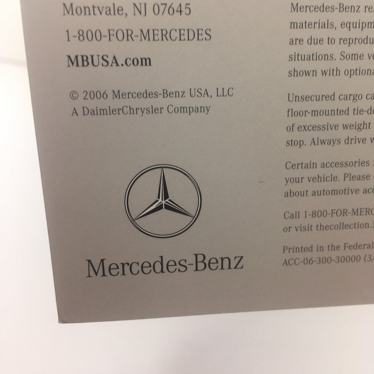 Close-up of the Mercedes-Benz logo on the back of the 2006 Mercedes-Benz SL-Class Accessories catalog with contact information.
