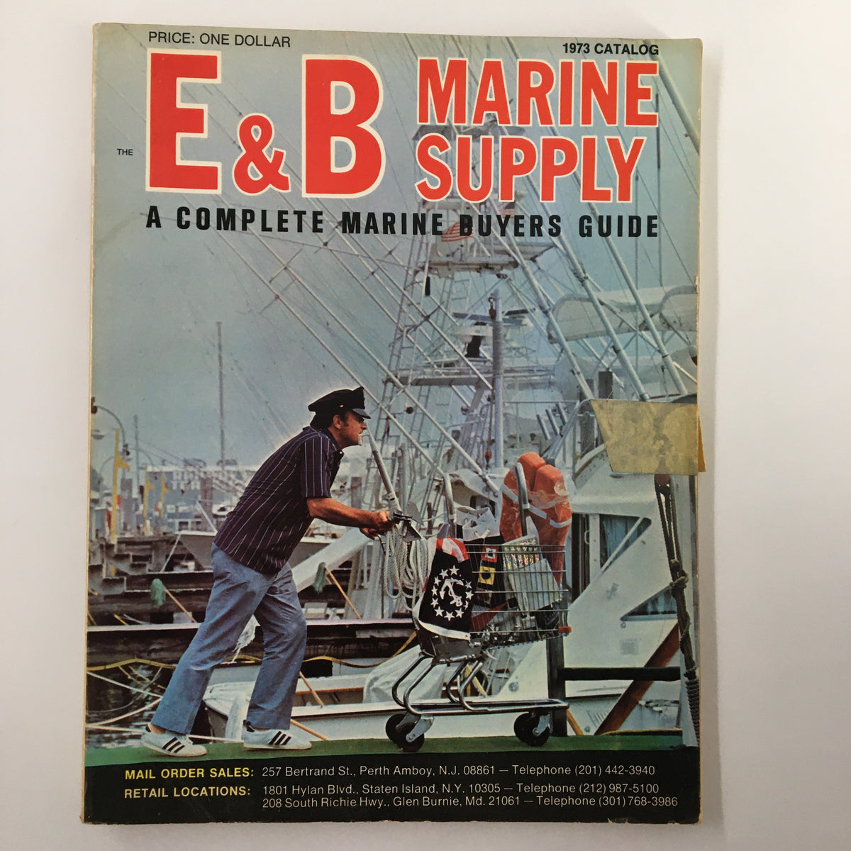 Cover image of the VTG 1973 E&B Marine Supply A Complete Marine Buyers Guide Catalog, featuring a vintage maritime scene with a man pushing a cart at a marina.