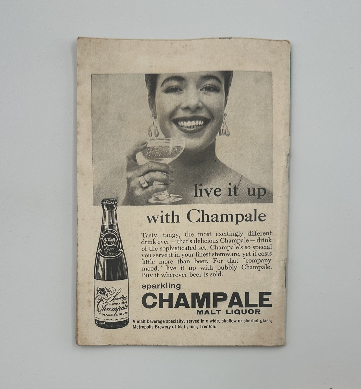 Jet Magazine January 3, 1957 advertisement for Champale Malt Liquor showing a beautiful woman enjoying a drink, promoting the beverage with a sophisticated appeal.
