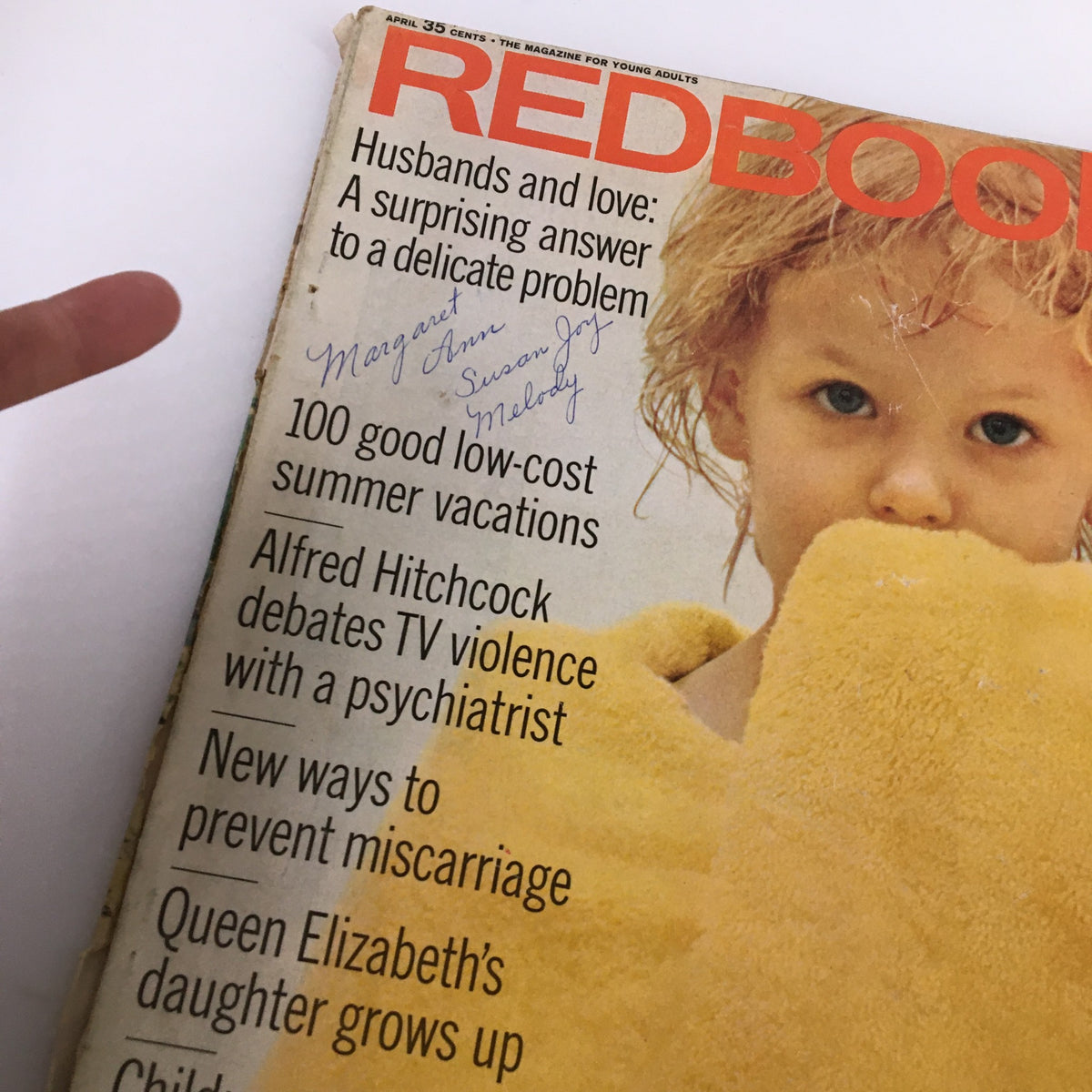 Close-up of the vintage Redbook Magazine cover from April showcasing a child wrapped in a yellow towel, focusing on Alfred Hitchcock's insightful discussion on TV violence. The cover also features handwritten notes, adding character to this collectible magazine.