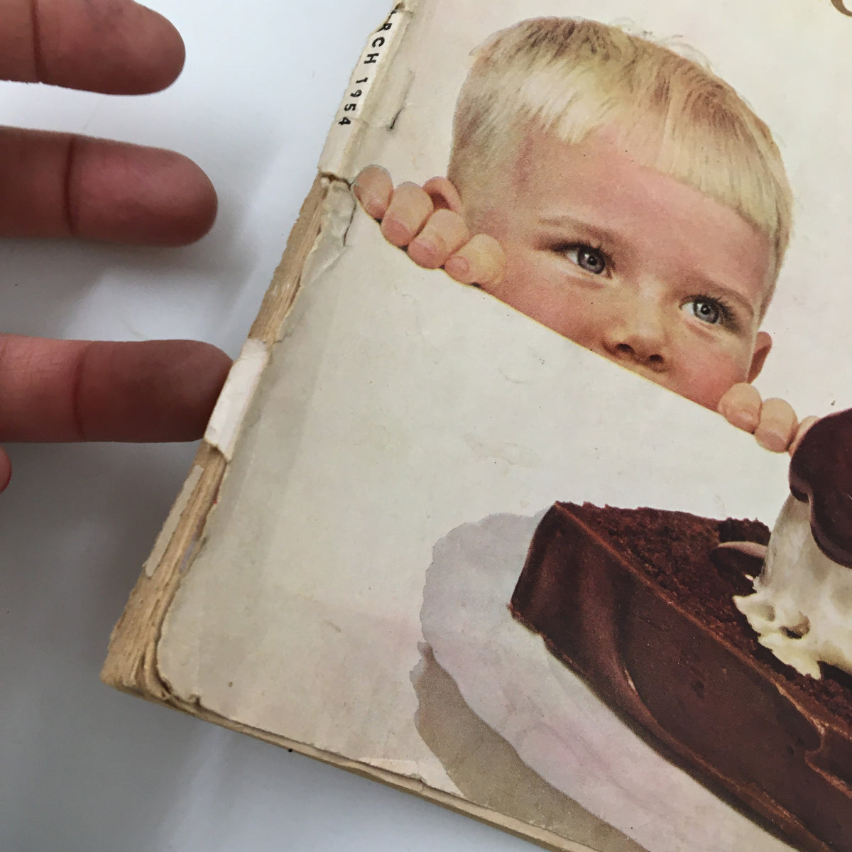 Close-up of VTG Woman's Day Magazine March 1954 cover, highlighting a child reaching for a chocolate dessert, illustrating the magazine's focus on sweet recipes.