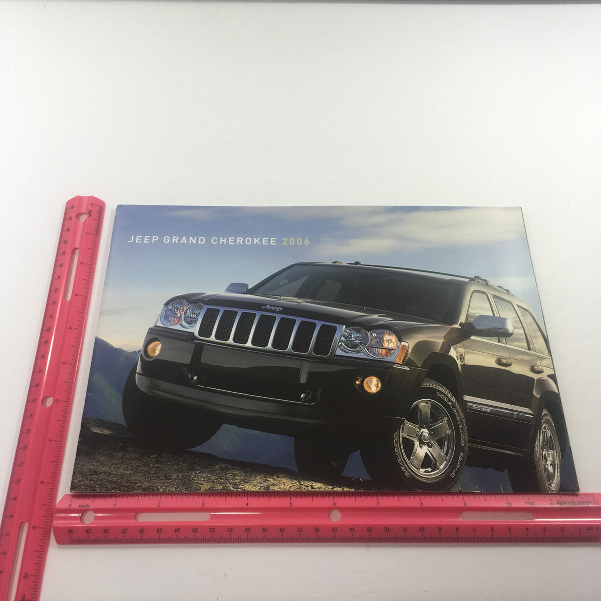 2006 Jeep Grand Cherokee Dealership Car Auto Brochure Catalog shown beside a ruler to indicate dimensions, emphasizing its size and design.