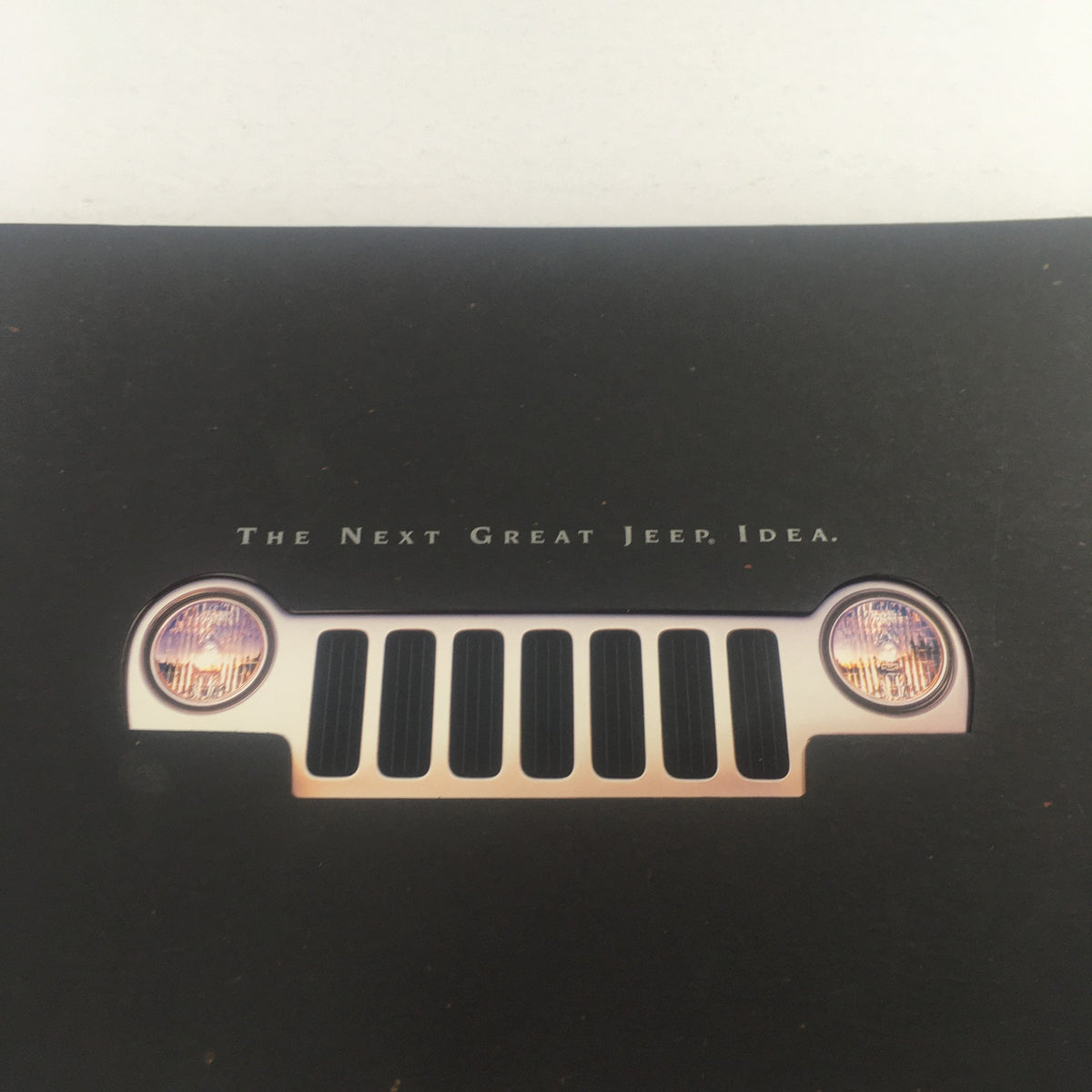 Close-up view of the Jeep grille and headlights on the 2002 Jeep Liberty Dealership Car Auto Brochure Catalog with the tagline 'The Next Great Jeep Idea.'
