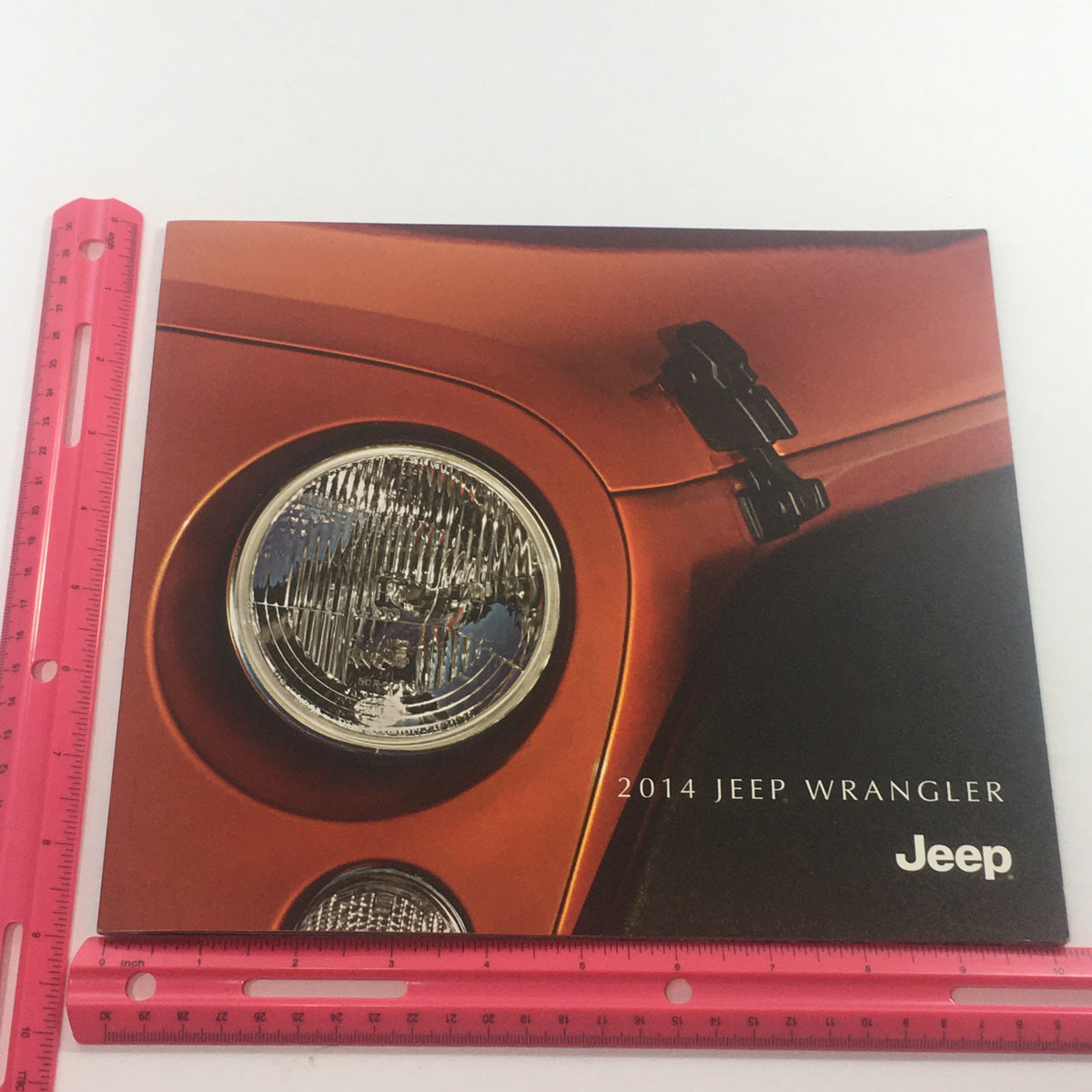 2014 Jeep Wrangler 4x4 Dealership Car Auto Brochure Catalog placed next to a ruler for size reference, showcasing its cover design.
