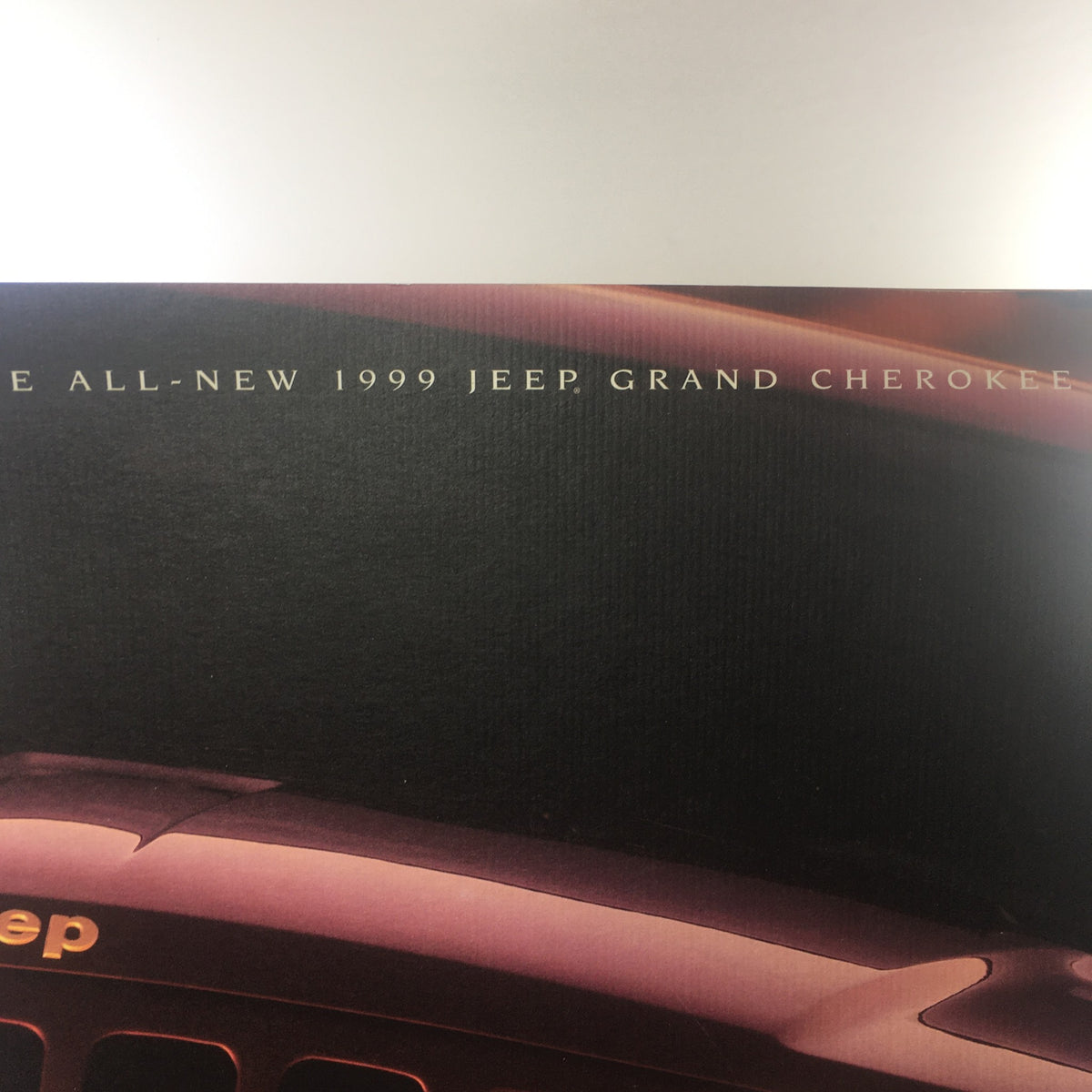 Close-up of the title on the 1999 Jeep Grand Cherokee SUV Dealership Car Auto Brochure Catalog emphasizing its all-new features.
