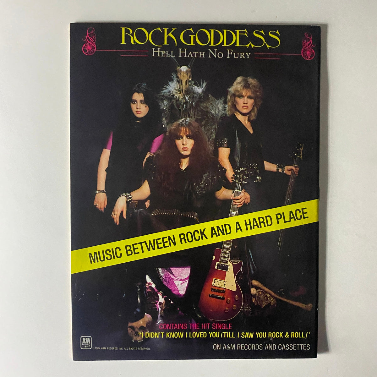 Rock Goddess album cover 'Hell Hath No Fury,' featuring the female rock band with the tagline 'Music Between Rock and a Hard Place,' reflecting 1980s rock aesthetics.