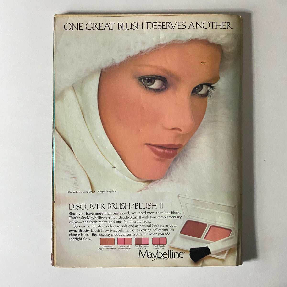 16 Magazine December 1980 advertisement for Maybelline, displaying a model with dramatic makeup and a winter hat, promoting the Brush/Blush II cosmetic line.