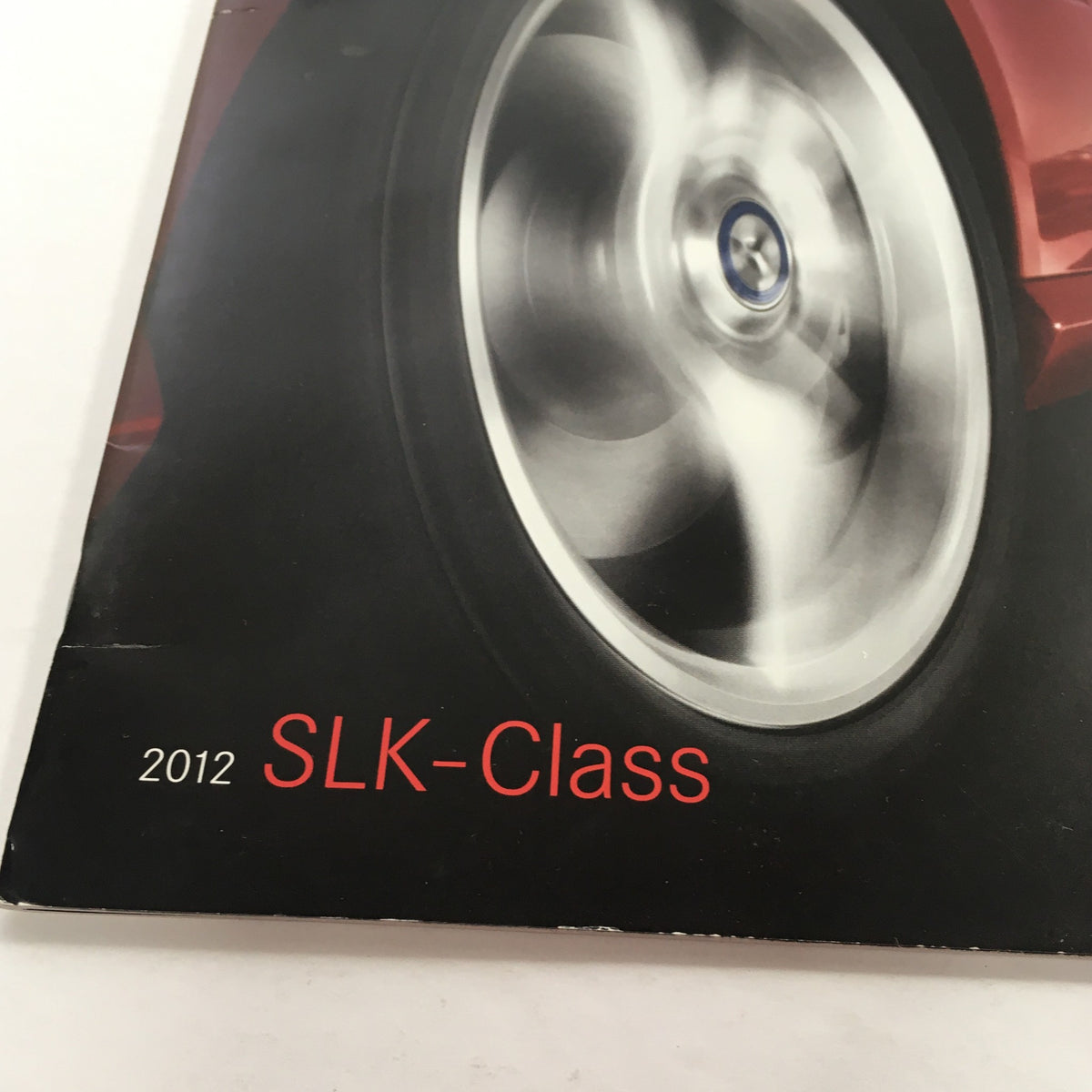 Close-up image of the 2012 Mercedes-Benz SLK-Class Dealership Car Auto Brochure Catalog, highlighting the sleek wheel design with the title '2012 SLK-Class' prominently displayed.