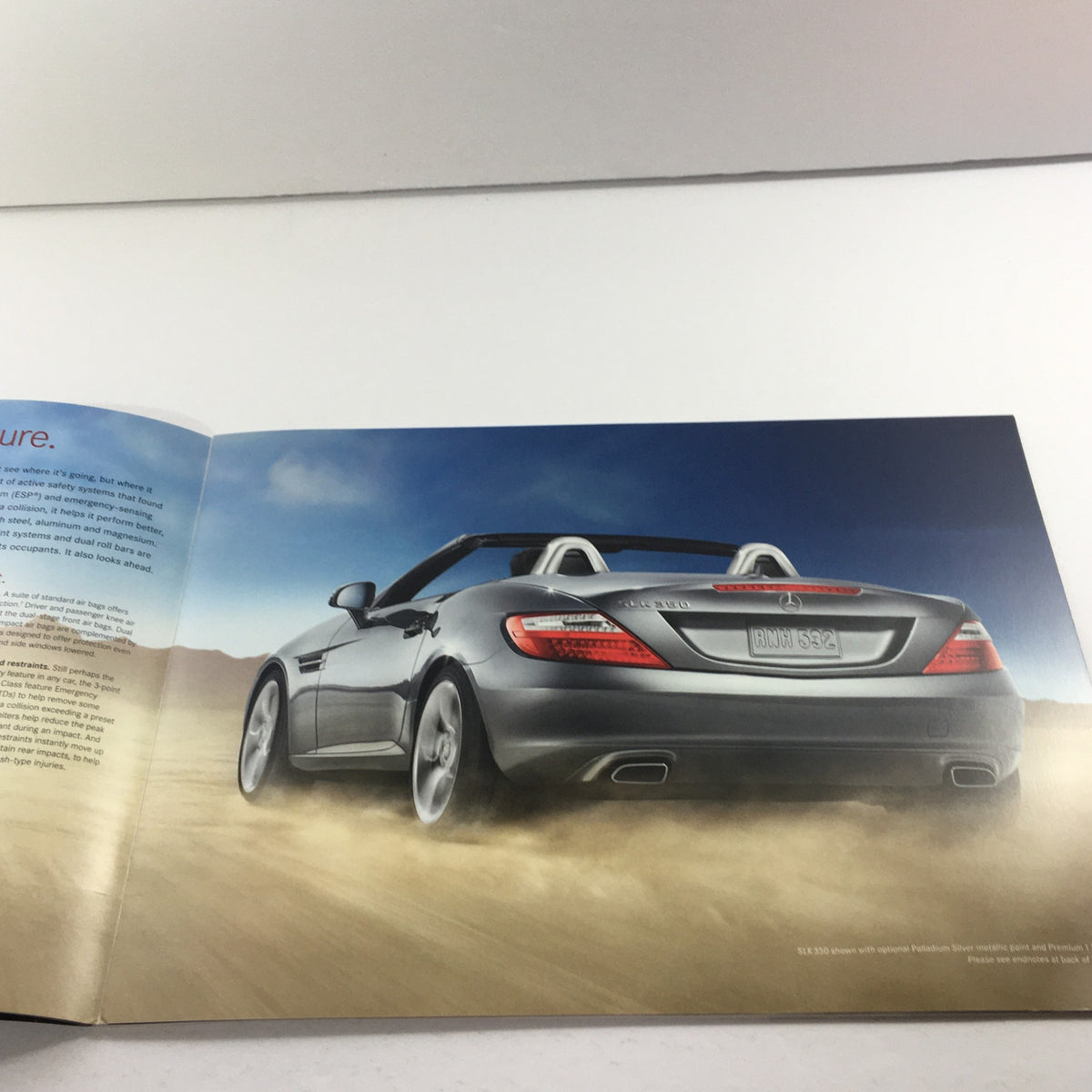 Inside page of the 2012 Mercedes-Benz SLK-Class Dealership Car Auto Brochure Catalog featuring a silver SLK-Class convertible driving on a sandy terrain, illustrating versatility and elegance.