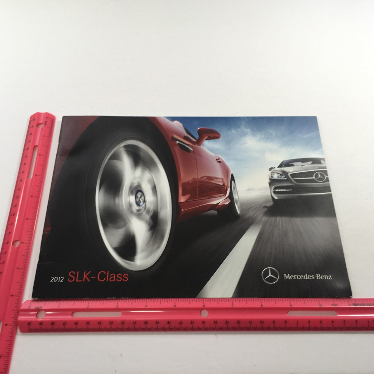 2012 Mercedes-Benz SLK-Class Dealership Car Auto Brochure Catalog showcasing dynamic photography of a red SLK-Class car in motion, highlighting its sporty design.