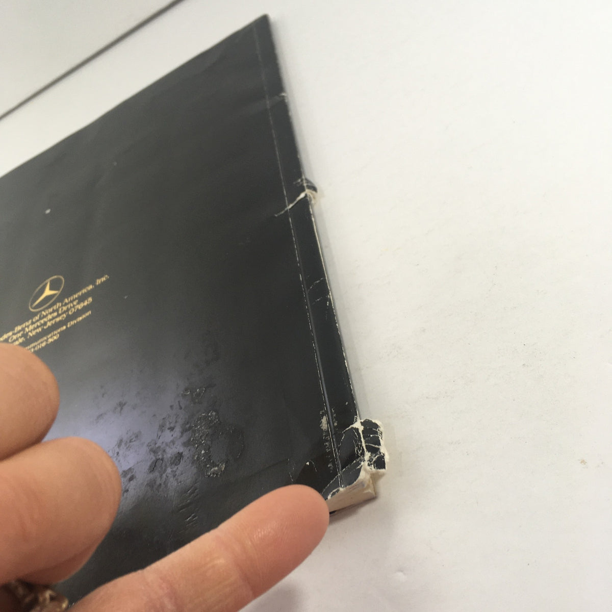 Close-up of the worn edge of the vintage 1984 Mercedes-Benz 190E 2.3/190D 2.2 Sedans Dealership Car Auto Brochure Catalog showing authenticity.
