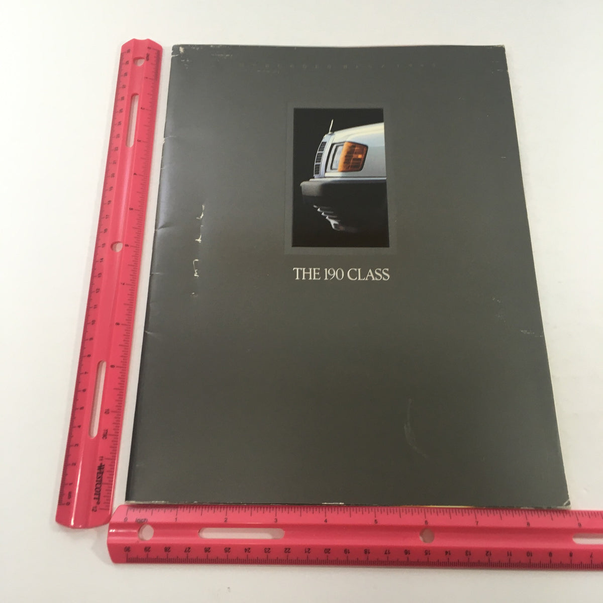 1989 Mercedes-Benz 190-Class 190E 2.6 Sedan Dealership Car Auto Brochure Catalog showing the front cover next to a ruler for size comparison.