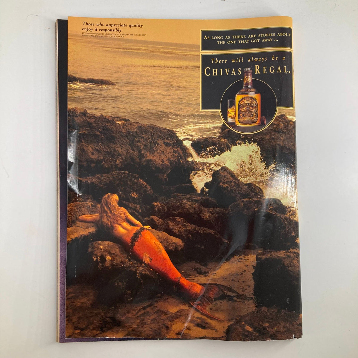 Cover of Chivas Regal advertisement featuring a mermaid relaxing on rocks by the ocean. The image complements the luxury spirit branding, perfect for collectors of vintage magazines.