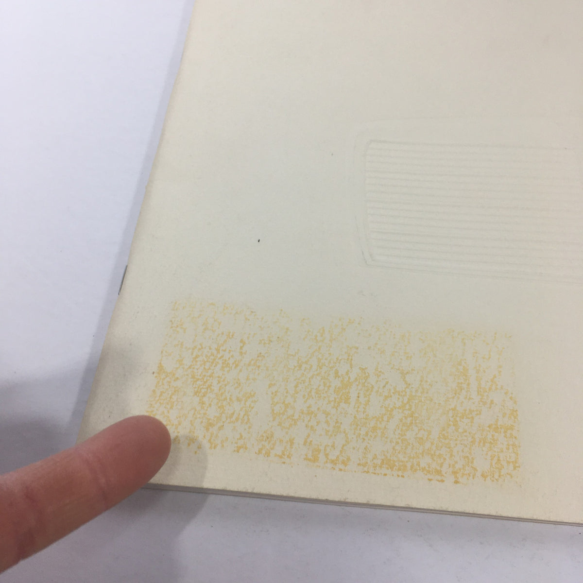 Image showing a finger pointing at a faded mark on the back cover of the 1980 Mercedes-Benz 280CE dealership car brochure catalog.