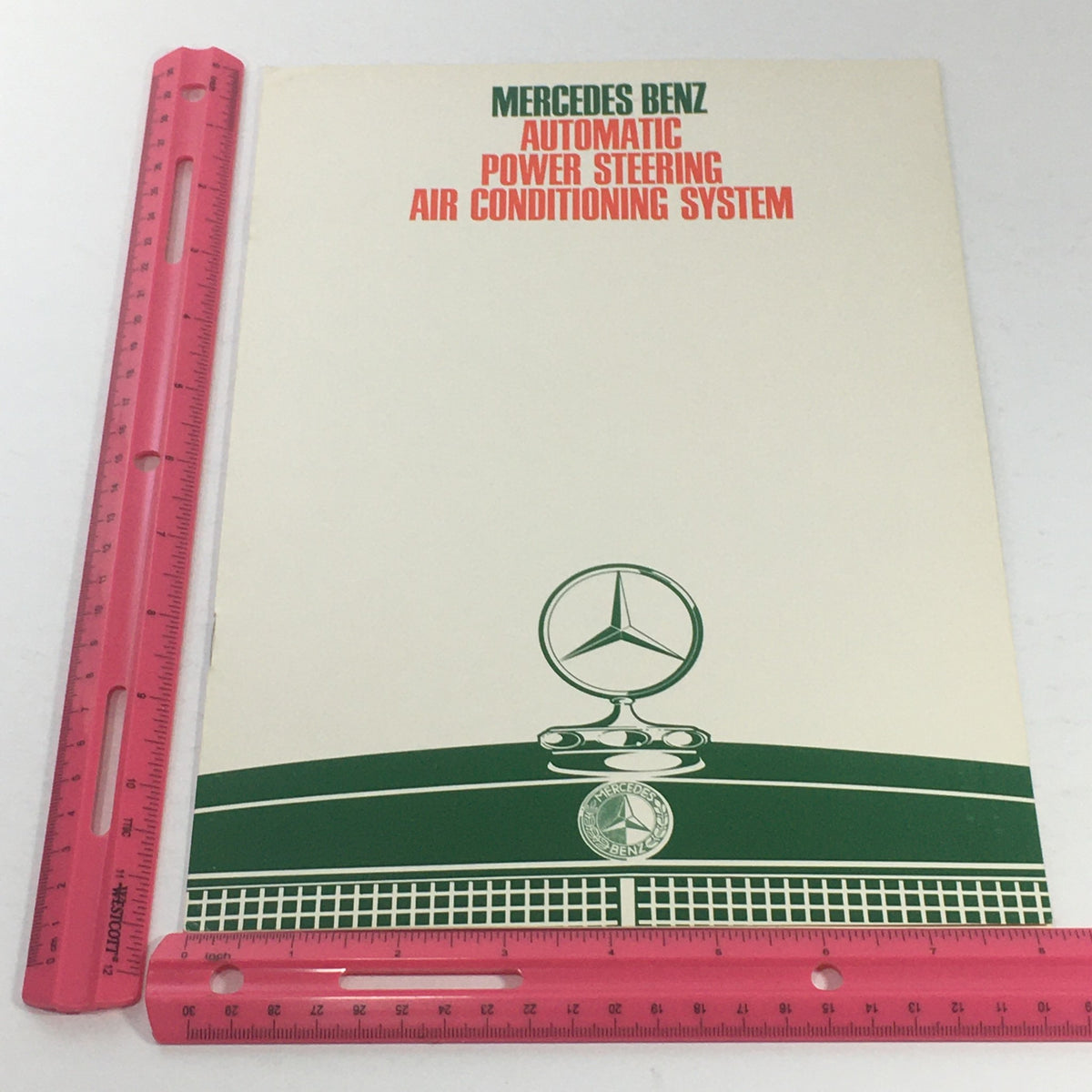 1980s Mercedes-Benz AT/Power Steering Dealership Car Auto Brochure Catalog alongside a ruler for size reference, showcasing its dimensions.