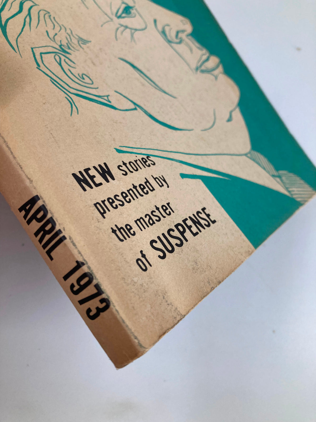 Side view of the April 1973 issue of Alfred Hitchcock's Mystery Magazine, highlighting the publication date and description of new stories.