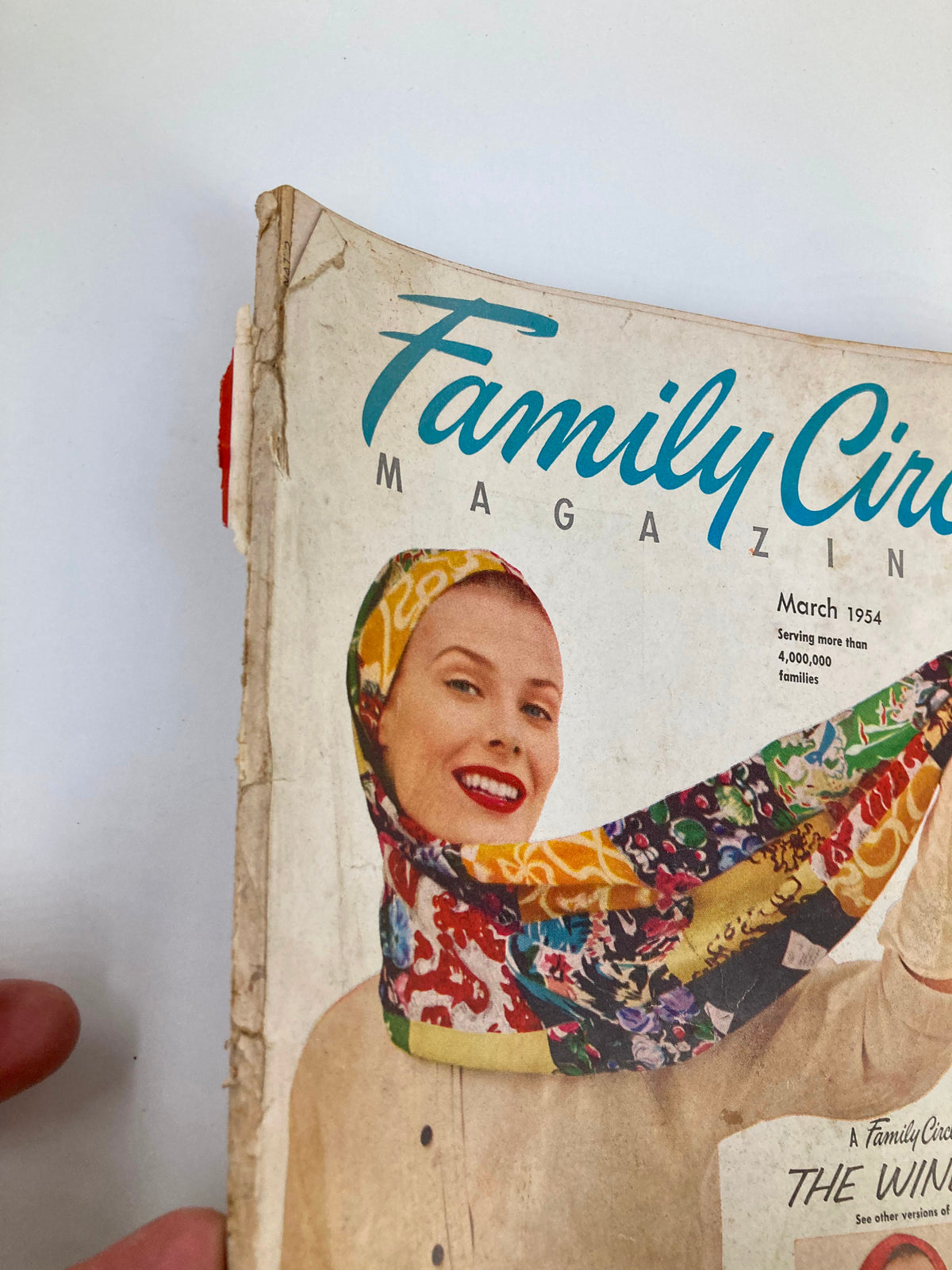 Close-up of the cover of VTG Family Circle Magazine March 1954, displaying a woman with lipstick smiling and showcasing a patterned scarf.