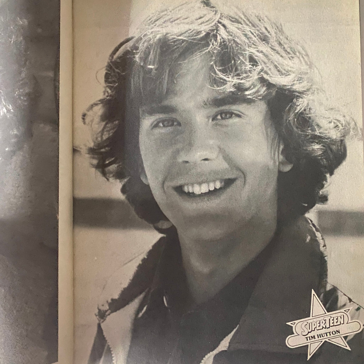 Black and white image of Tim Hutton from SuperTeen Pinup Book No. 2, smiling with a charming demeanor, embodying the teen idol essence.
