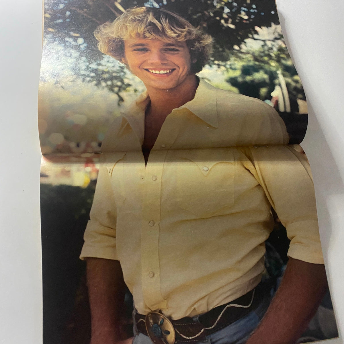 Inside page of Teen Bag Magazine March 1981 showing a full-color poster of John Schneider smiling in a yellow shirt, celebrating 1980s teen culture and nostalgia.