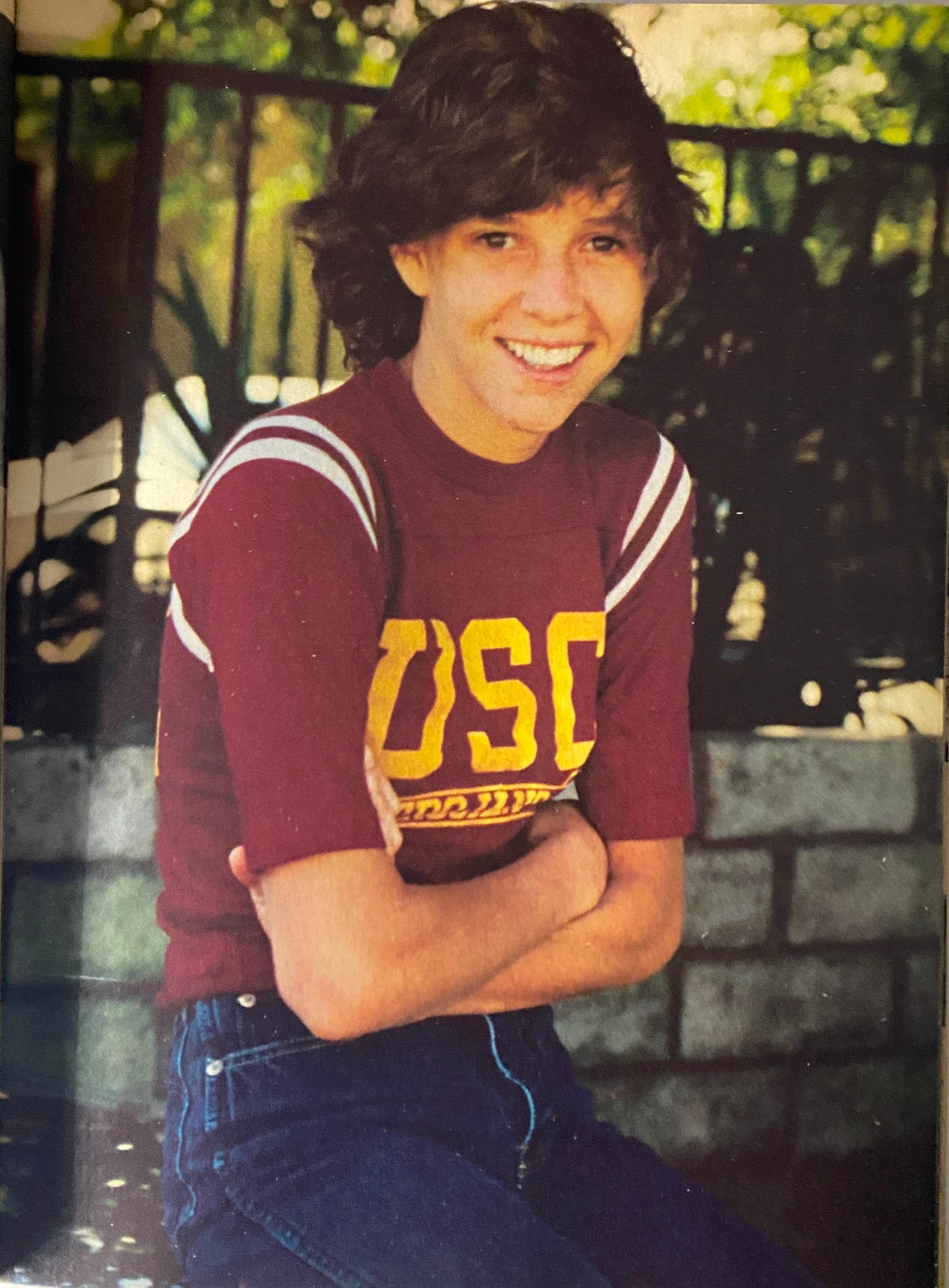 A young male with short curly hair smiling while wearing a USC shirt, featured in the Teen Bag Magazine May 1981.