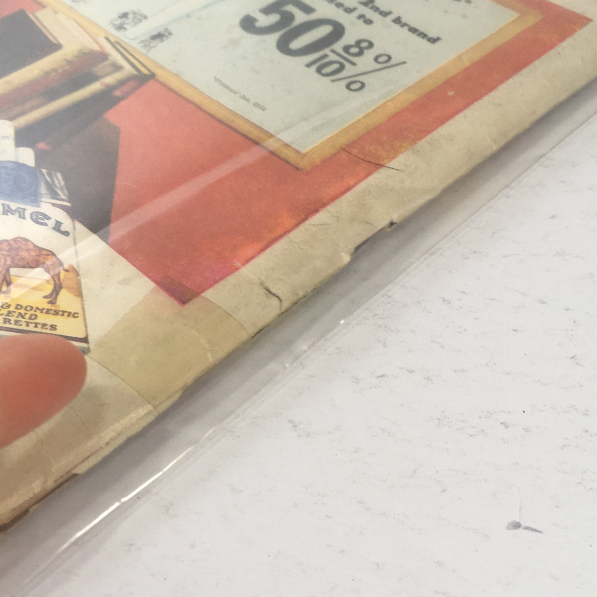Close-up view of the edge of the Life Magazine from May 3, 1954, showcasing its vintage wear and tear, including a visible cigarette advertisement and signs of aging, emphasizing its historical context as a collectible featuring eight pages of the world's rarest stamps.