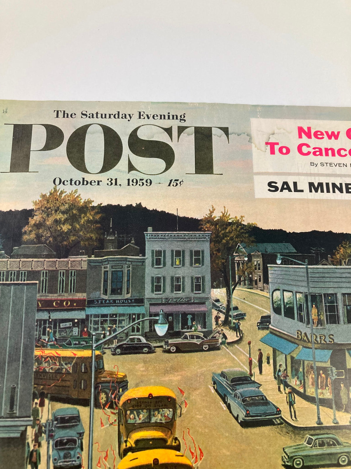 Close-up of The Saturday Evening Post cover from October 31, 1959, featuring 'New Clues To Cancer Cures,' showing a town street with a parade, historic cars, and colorful storefronts.